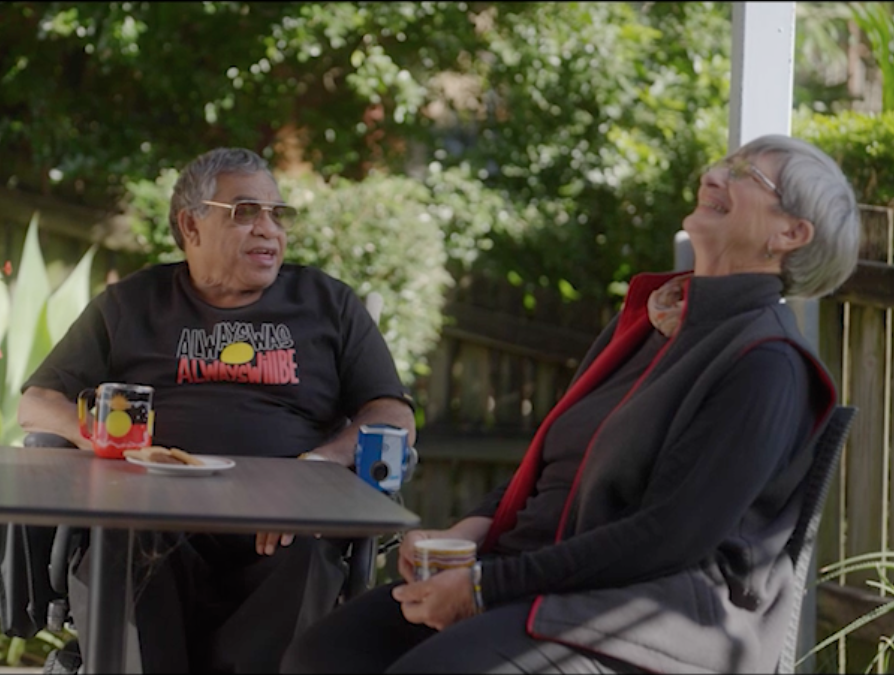 Two people sitting outdoors having tea.